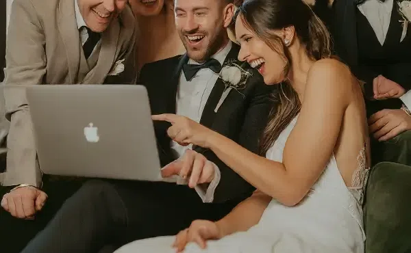 Happy wedding  couple watching on the laptop with their guest